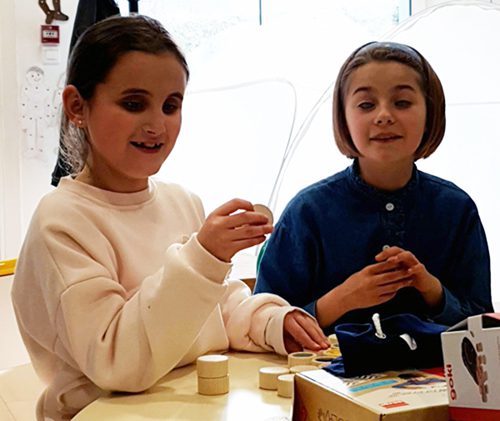Carmela à gauche et Anne à droite jouent à un jeu de société en braille